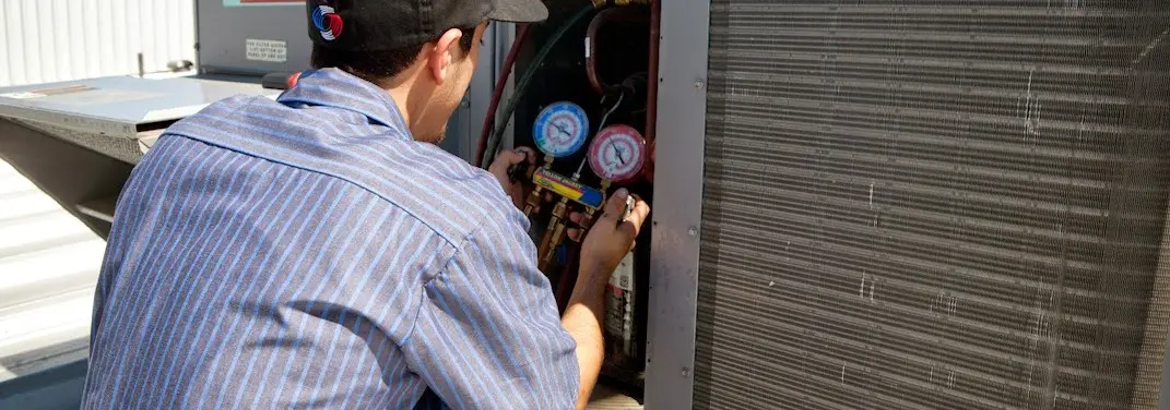 HVAC technician servicing a condenser unit in Othello