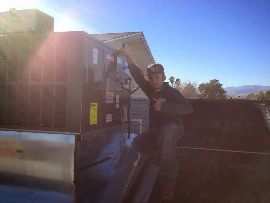 HVAC technician performing Air Duct Cleaning on a rooftop unit in Othello